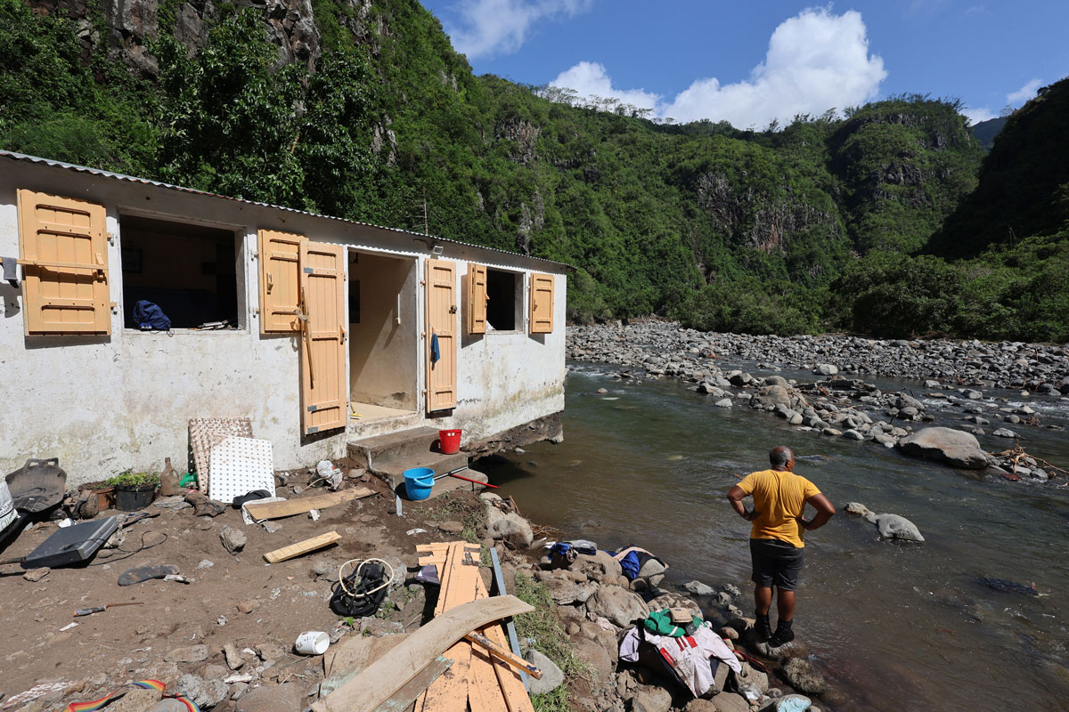 Un habitant les pieds dans l’eau près d’une maison endommagée par les crues provoquées par le cyclone Garance en mars 2025