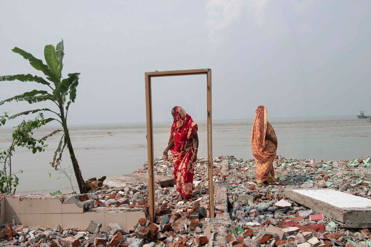 Deux femmes se tiennent sur les restes d’une maison détruite par l’érosion en bordure du fleuve Padma, Bangladesh