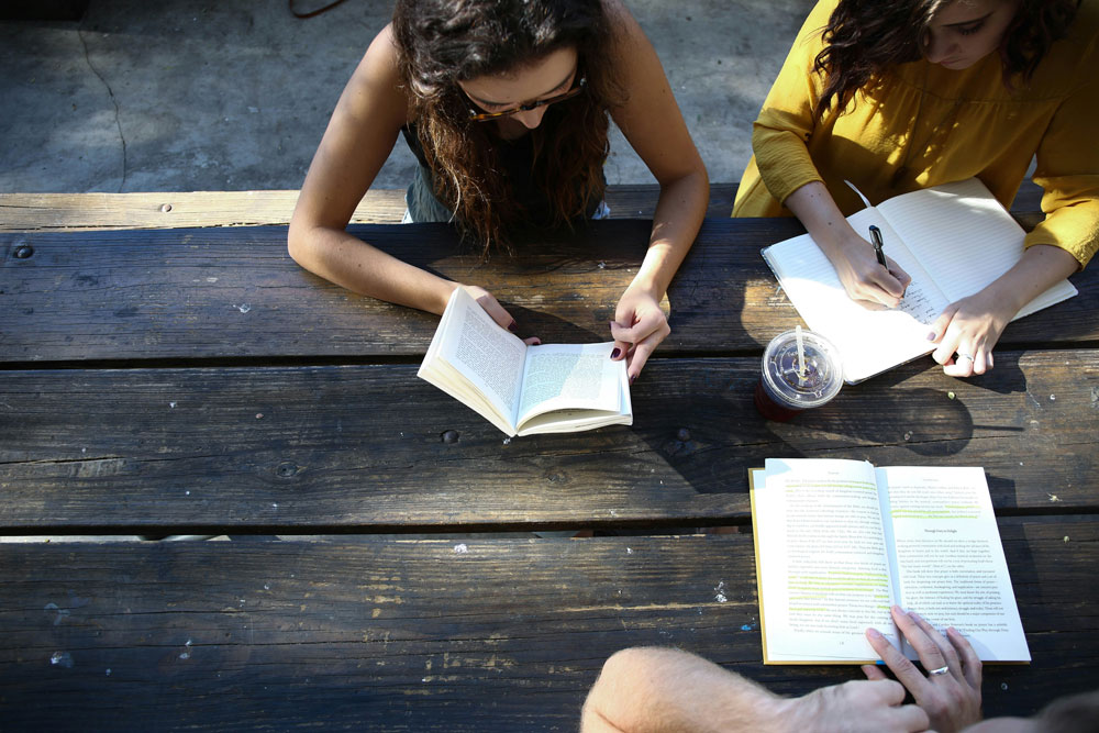 Femmes lisant des livres posés sur une table en bois, vue de dessus