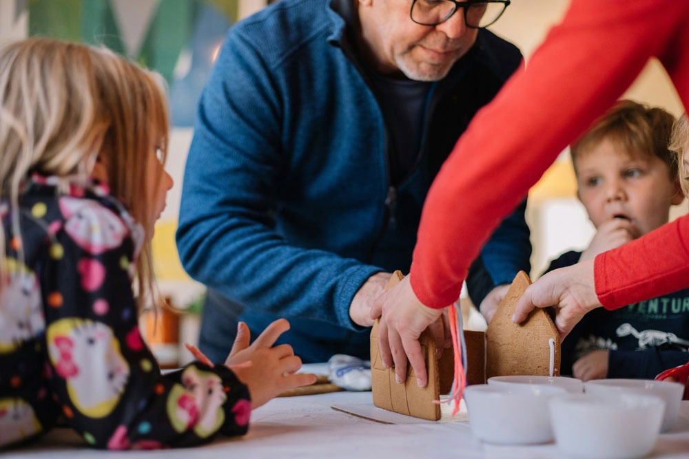 Adultes faisant une maison en pain d’épice avec trois enfants