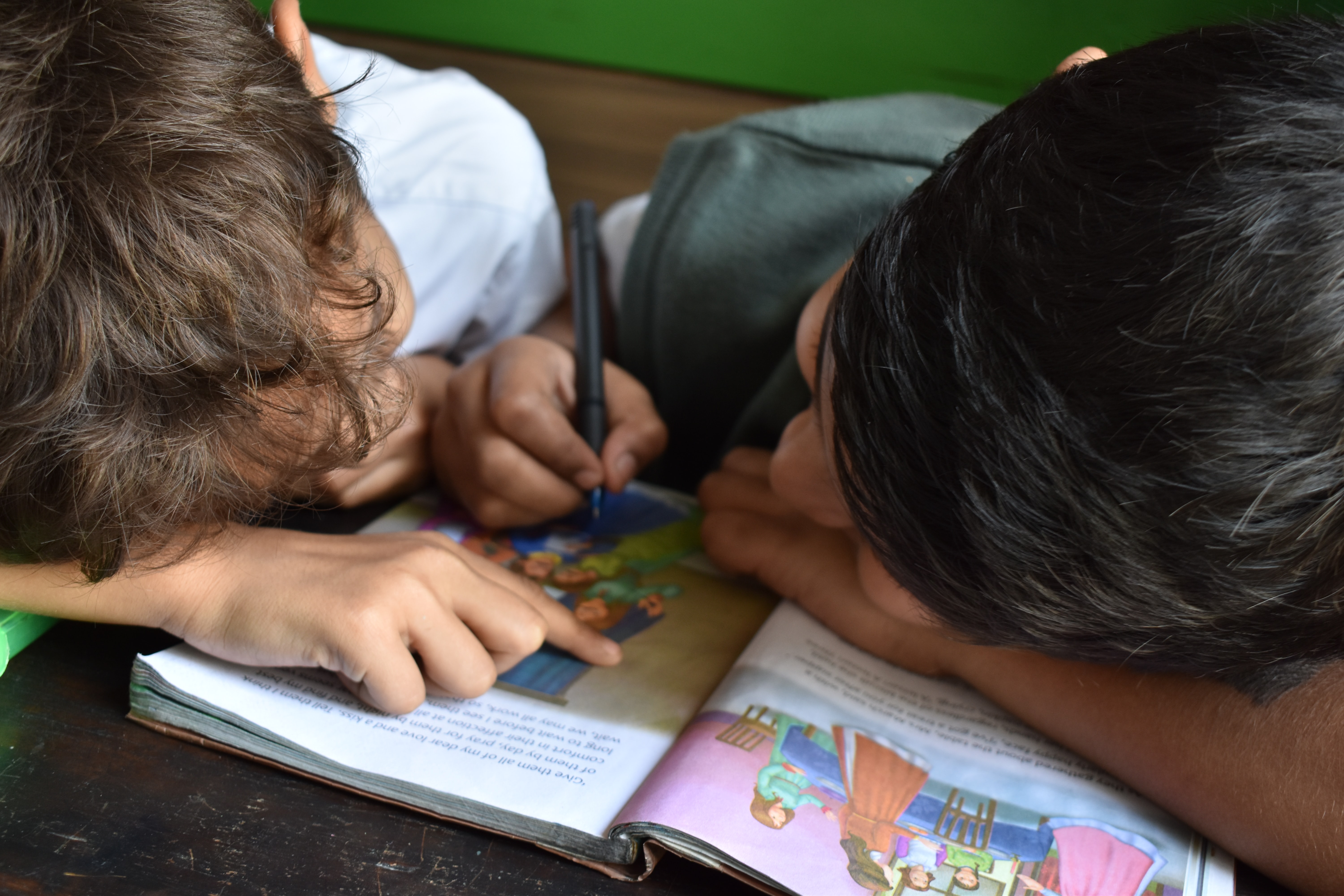 Deux enfants devant un cahier travaillant ensemble.