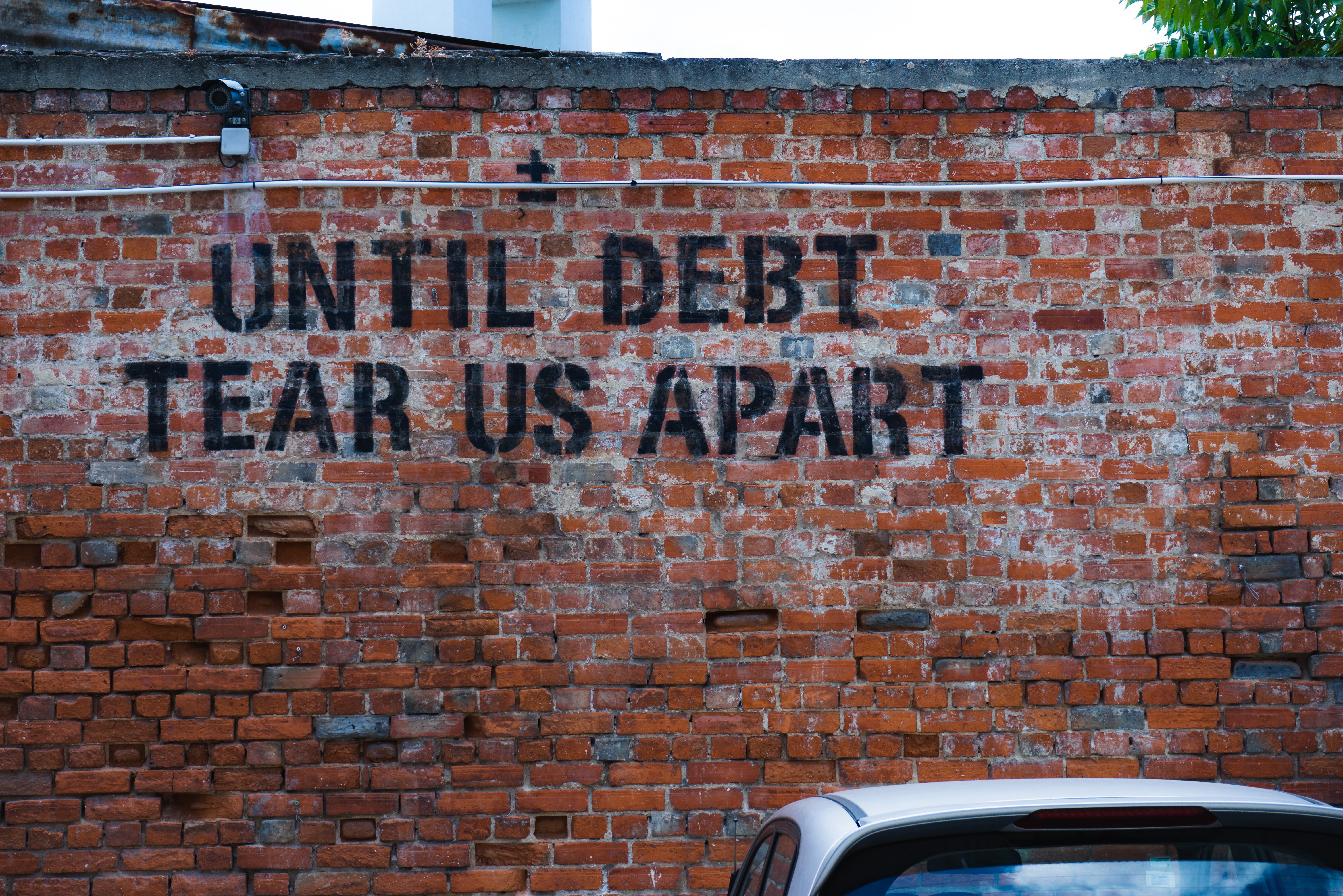 Photo d'un mur taggé " Until debt tear us appart"