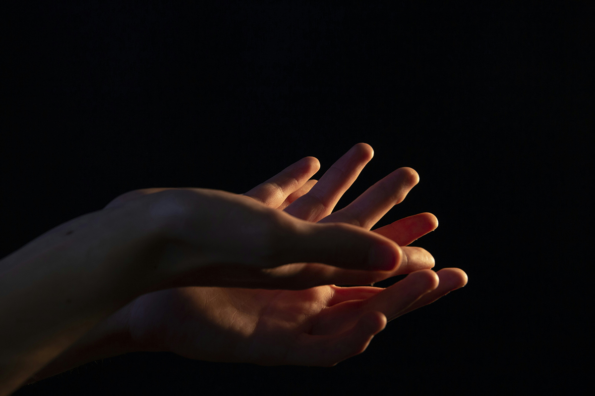 Deux mains mêlées sur un fond noir. Photo © Flavie Martin sur Unsplash
