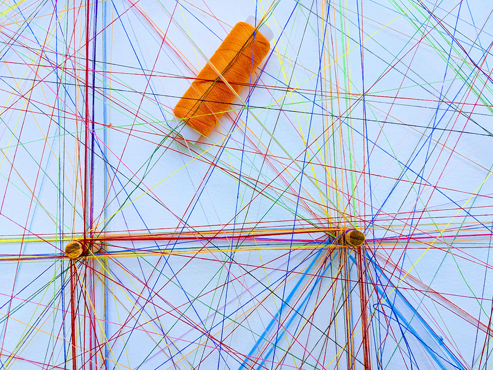 Ensemble de fil de couleurs formant des réseaux avec des épingles pour illustrer des nœuds d’interactions