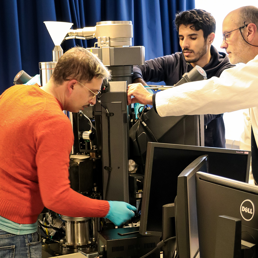 Trois personnes manipulent un spectromètre en vue de son transfert.