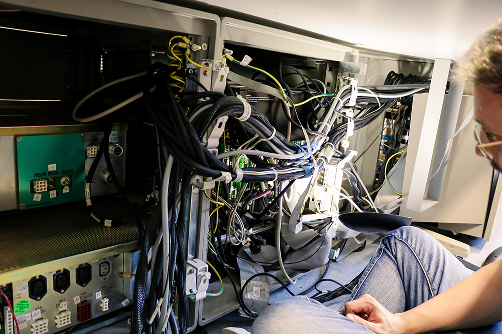 Une personne assure le décâblage d'un spectromètre avant qu'il ne soit transféré.