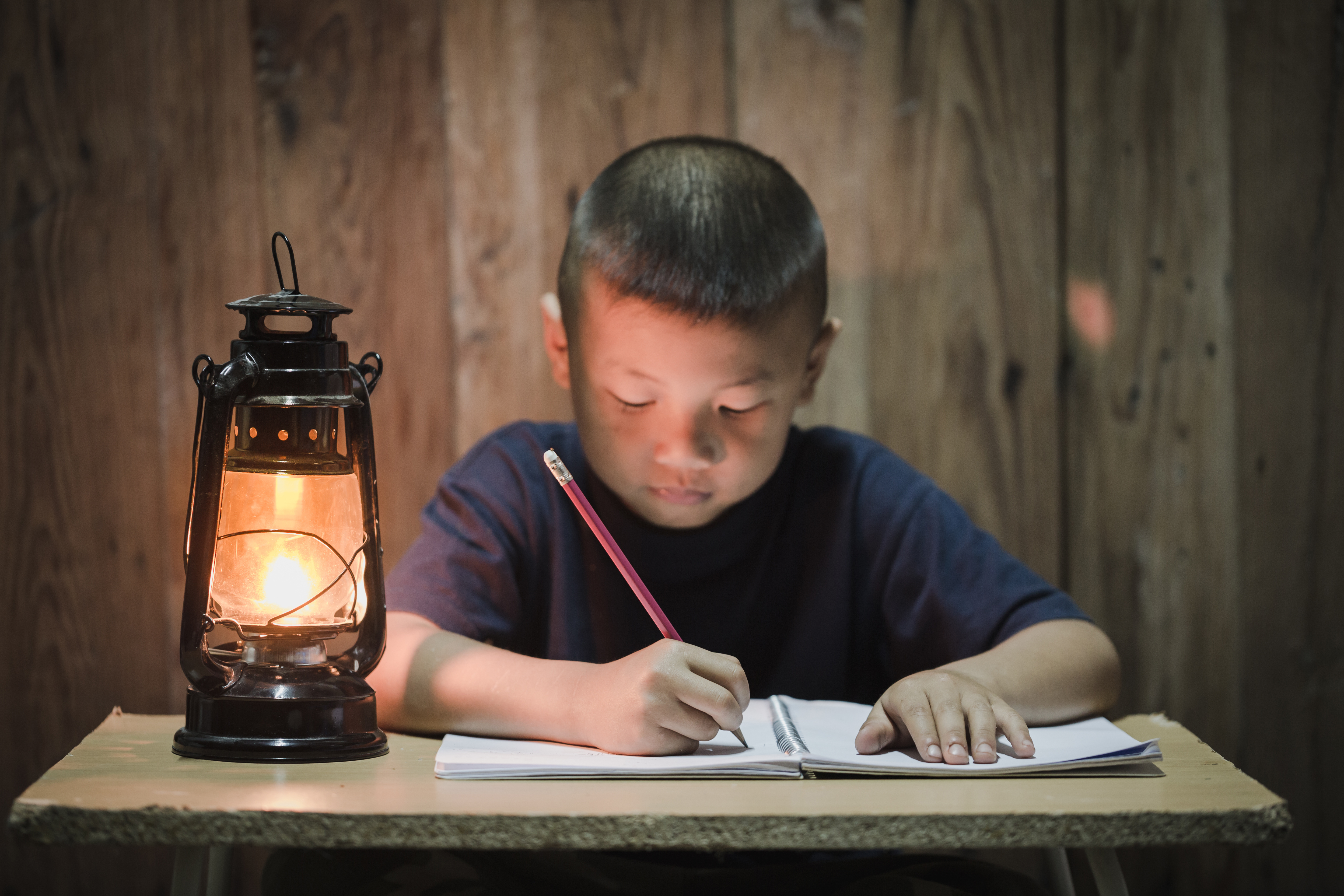 jeune garçon d'Asie centrale travaillant éclairé par une lanterne