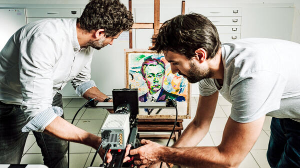 Installation d’une caméra particulière, un imageur multispectral de photoluminescence, par deux chimistes du patrimoine ; au fond on voit un tableau de R. Delaunay.