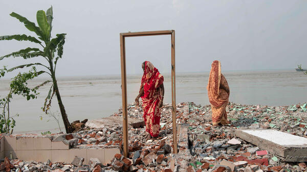 Deux femmes se tiennent sur les restes d’une maison détruite par l’érosion en bordure du fleuve Padma, Bangladesh