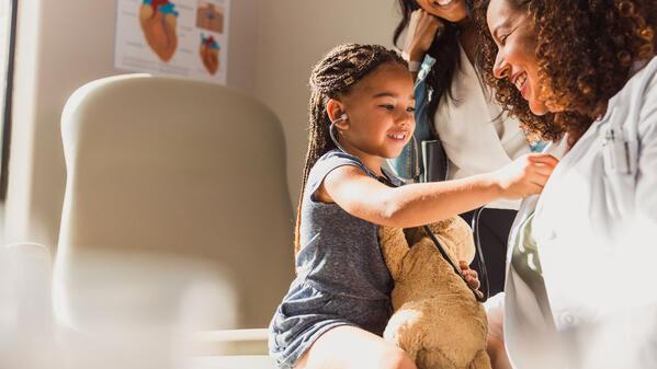 Une enfant écoute le coeur de son médecin avec un stéthoscope