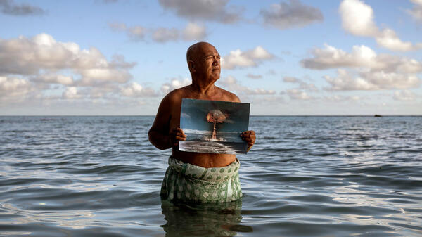 Angelo Tehuira-Hioe, 64 ans, tient une photo d’une explosion nucléaire © Adam Ferguson / The New York Times-Redux / RÉA