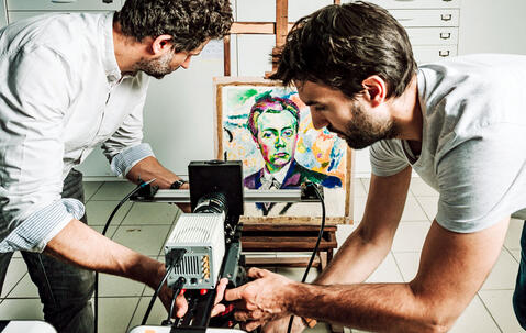 Installation d’une caméra particulière, un imageur multispectral de photoluminescence, par deux chimistes du patrimoine ; au fond on voit un tableau de R. Delaunay.