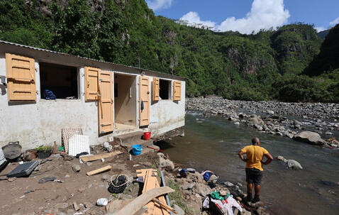Un habitant les pieds dans l’eau près d’une maison endommagée par les crues provoquées par le cyclone Garance en mars 2025