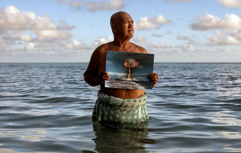 Angelo Tehuira-Hioe, 64 ans, tient une photo d’une explosion nucléaire © Adam Ferguson / The New York Times-Redux / RÉA