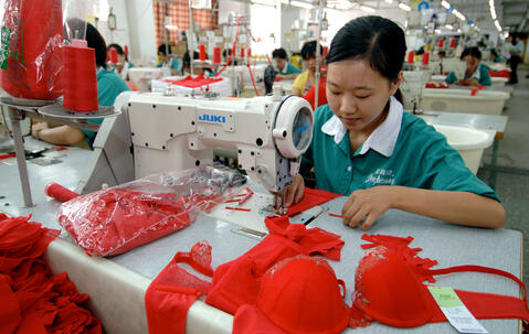 Une femme coud un soutien-gorge rouge dans usine textile en Chine.