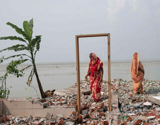 Deux femmes se tiennent sur les restes d’une maison détruite par l’érosion en bordure du fleuve Padma, Bangladesh