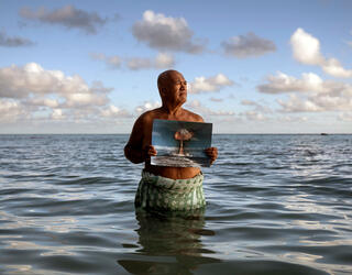 Angelo Tehuira-Hioe, 64 ans, tient une photo d’une explosion nucléaire © Adam Ferguson / The New York Times-Redux / RÉA