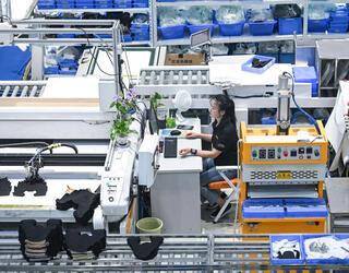 Une employée à un poste de travail réduit au minimum et semblant isolée au milieu des machines automatisées. Elle a placé des plantes pour humaniser son poste. © Zhou Yi / Xinhua-RÉA
