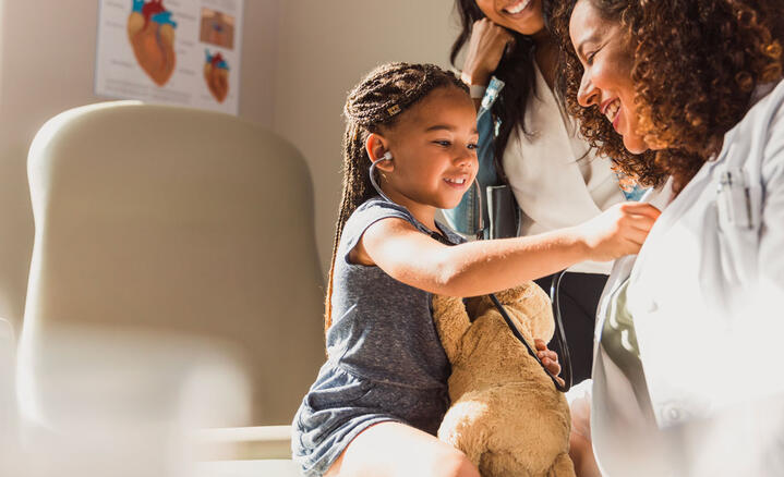Une enfant écoute le coeur de son médecin avec un stéthoscope
