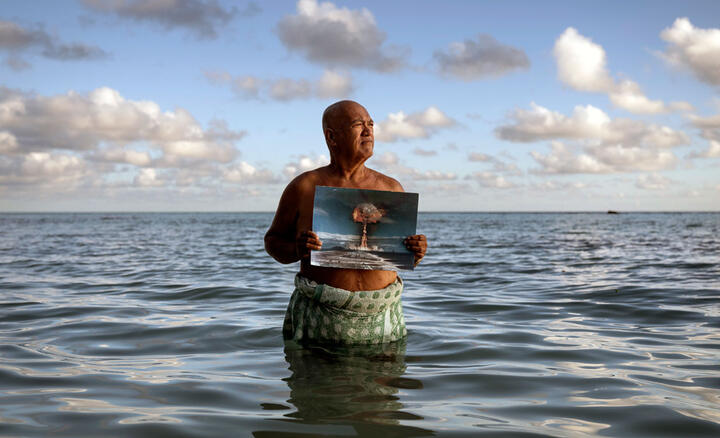 Angelo Tehuira-Hioe, 64 ans, tient une photo d’une explosion nucléaire © Adam Ferguson / The New York Times-Redux / RÉA