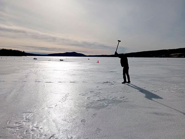 Sortie sur un lac gelé. Un chercheur frappe la glace à la masse afin d’y générer des vibrations. © Antonin Eddi, BicWin2024, Laboratoire PMMH, CNRS
