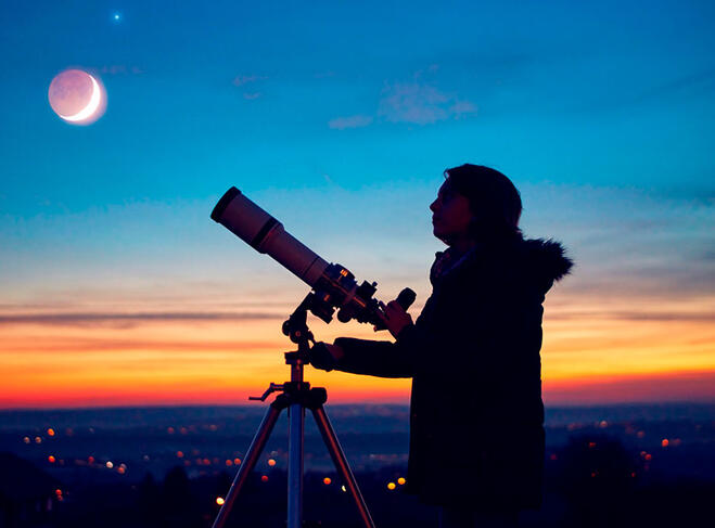 Un astronome amateur en ombre chinoise devant un ciel coloré de coucher de Soleil 