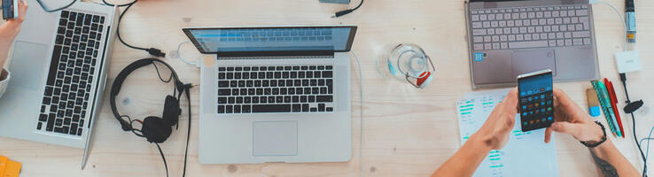 Table vue du dessus recouverte d’outils de communication, ordinateurs, smartphones © Marvin Meyer / Unsplash