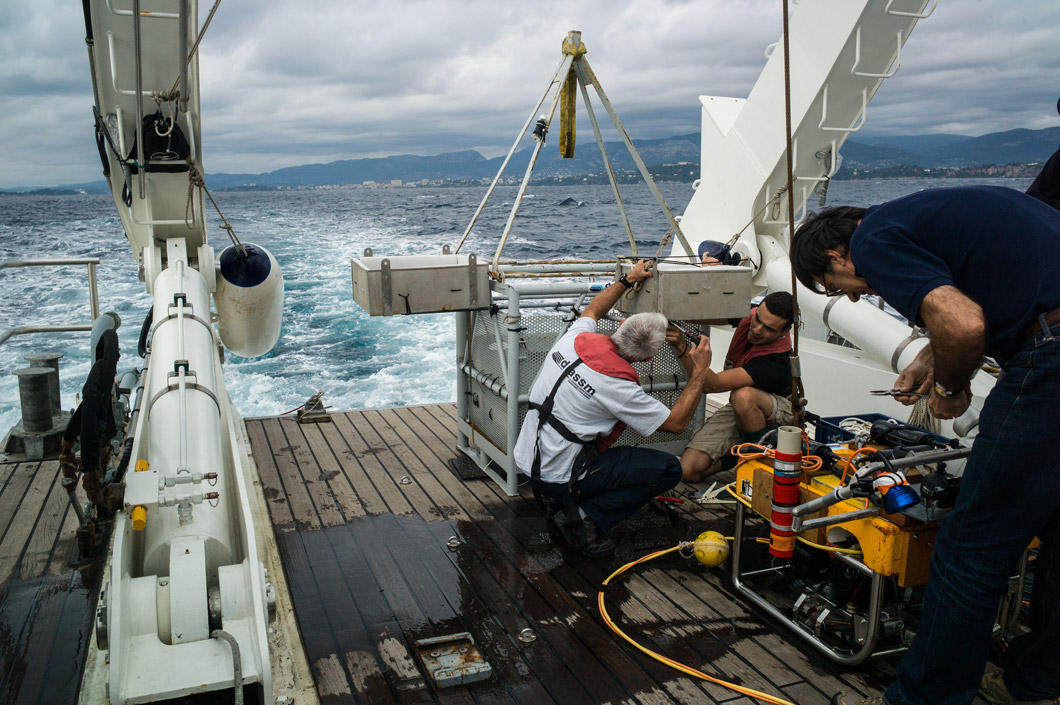 À l'arrière du bateau, des hommes manipulent des machines.