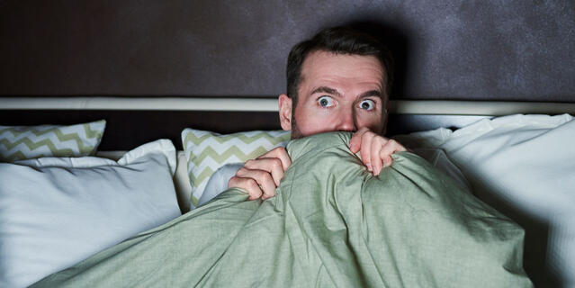 Un homme a peur en regardant un film d’horreur.