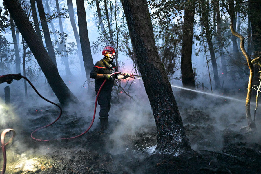Un pompier armé d’une lance à eau, dans la forêt de Brocéliande
