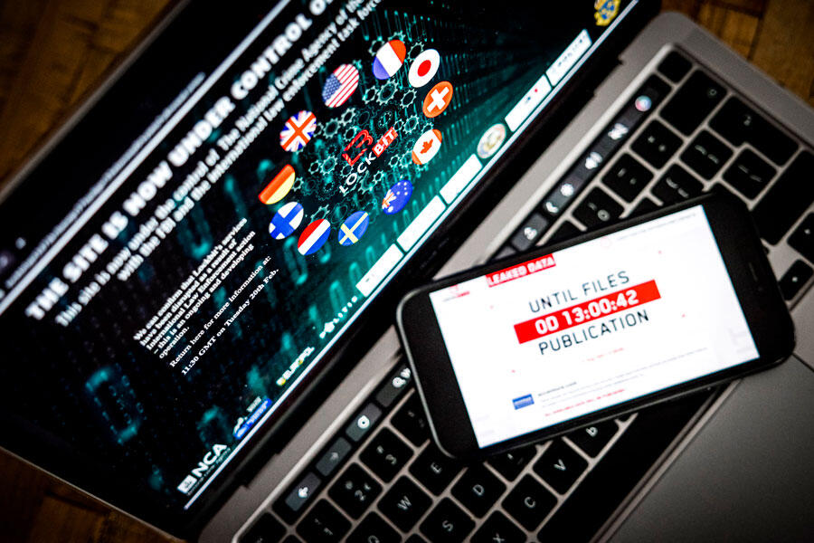 Écran de smartphone affichant le site Lockbit, le smartphone est posé sur le clavier d'un ordinateur portable.