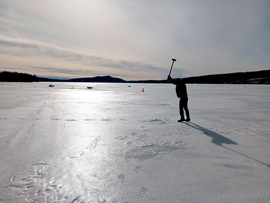 Sortie sur un lac gelé. Un chercheur frappe la glace à la masse afin d’y générer des vibrations. © Antonin Eddi, BicWin2024, Laboratoire PMMH, CNRS