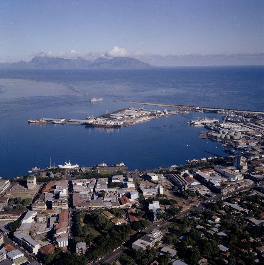 Vue aérienne du port de Papeete, avec la base navale et les installations du Centre d’expérimentations du Pacifique (CEP) sur les docks, mai 1976. © Pierre Ferrari / ECPAD / Défense / F 76-255 RC4