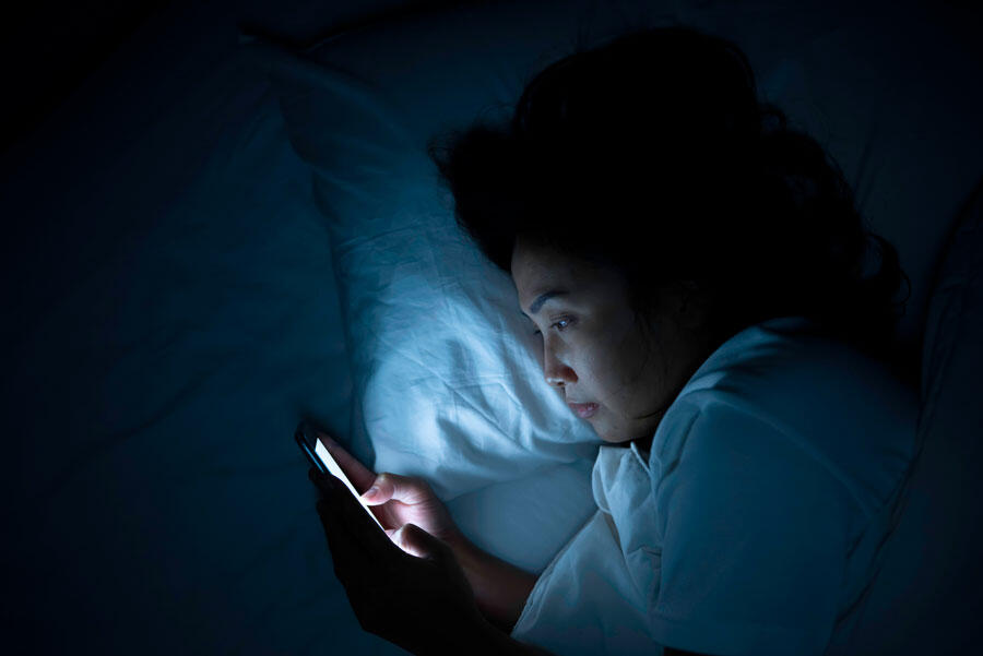 une femme scrolle son téléphone dans le noir