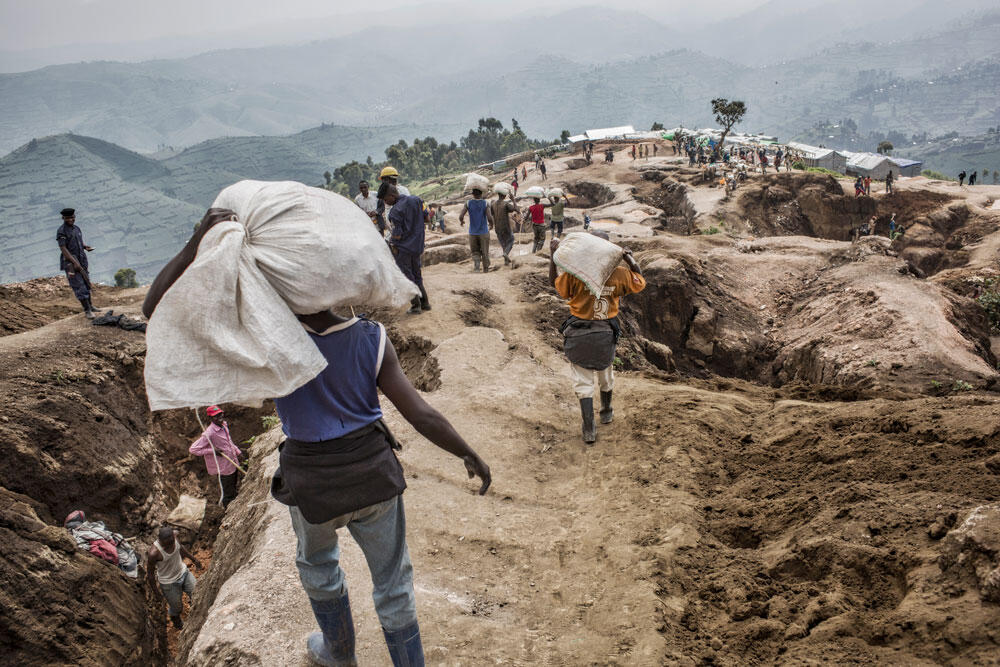 Un homme de dos porte un sac sur son épaule sur le site d'une mine au Nord-Kivu