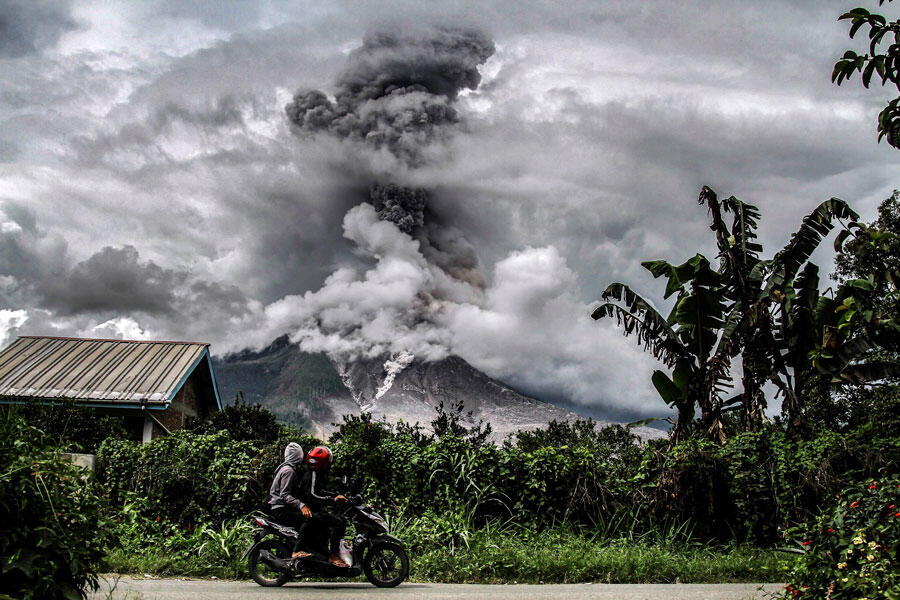 Un deux-roues devant une éruption du volcan Sinabung à Karo, Sumatra (Indonésie)