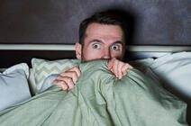 ©gpointstudio / iStockphoto.com Un homme a peur en regardant un film d’horreur.