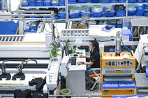 Une employée à un poste de travail réduit au minimum et semblant isolée au milieu des machines automatisées. Elle a placé des plantes pour humaniser son poste. © Zhou Yi / Xinhua-RÉA