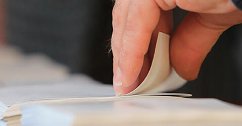 Gros plan sur une main qui prend des bulletins de vote l© Yves / stock.adobe.com