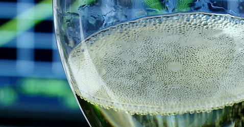 Bulles à la surface d'un verre de champagne placé devant l'écran d'un oscilloscope qui affiche des courbles