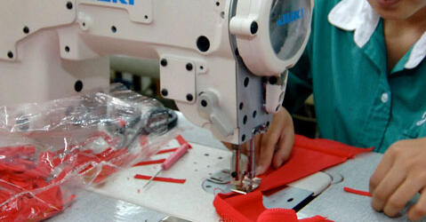 Une femme coud un soutien-gorge rouge dans usine textile en Chine.