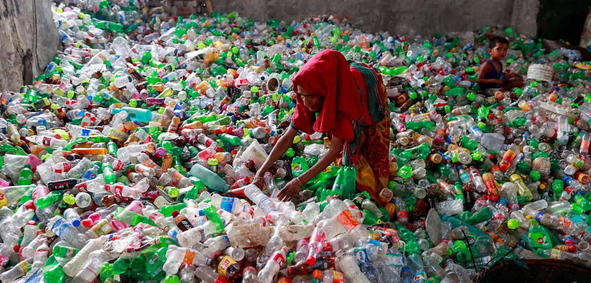 ©Suvra Kanti Das / ZUMA Press / RÉA Une femme trie des bouteilles en plastique avant leur recyclage, son enfant en arrière-plan sur l’amoncellement de bouteilles