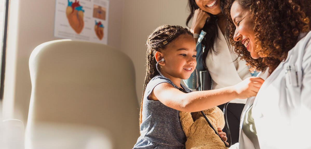 Une enfant écoute le coeur de son médecin avec un stéthoscope