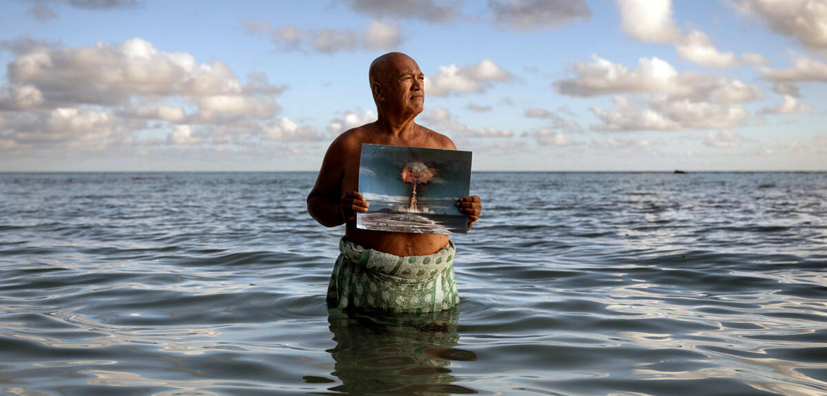 Angelo Tehuira-Hioe, 64 ans, tient une photo d’une explosion nucléaire © Adam Ferguson / The New York Times-Redux / RÉA