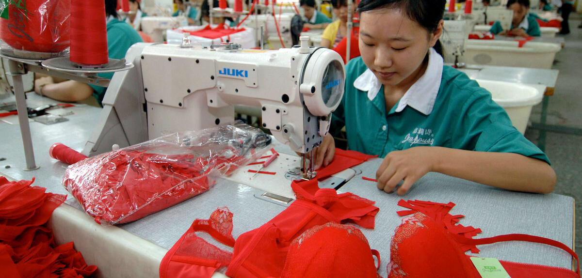 Une femme coud un soutien-gorge rouge dans usine textile en Chine.