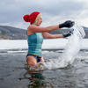 ©Halfpoint / iStockphoto.com Une femme avec des gants et un bonnet rouge se baignant dans un lac gelé