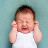 ©Irina Zharkova31 / Shutterstock.com Un bébé pleurant, les poings sur les oreilles et les yeux froncés